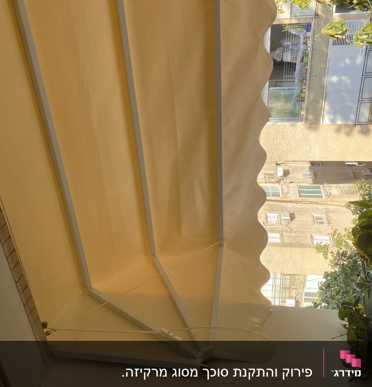סוכך צהוב עם מסגרת מתכת לבנה במרפסת